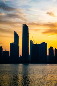 Modern buildings by sea against sky during sunset in abudhabi united arab emirates 