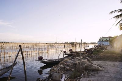 Fishing boats moored at harbor against sky