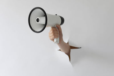 Close-up of hand holding camera against white background