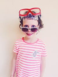 Portrait of cute girl wearing sunglasses and swimming goggles against wall