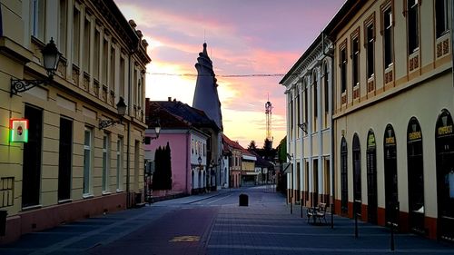 Statue in city against sky at sunset