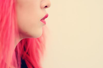 Side view midsection of young woman with redhead against wall