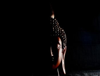 Close-up of buddha statue in darkroom