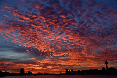 Silhouette buildings against dramatic sky during sunset