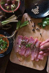 Cropped image of hand marinating meat on cutting board in kitchen