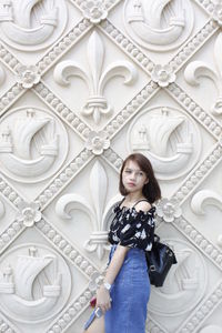 Portrait of woman standing against white wall