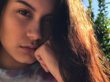 Close-up portrait of young woman with hand on chin