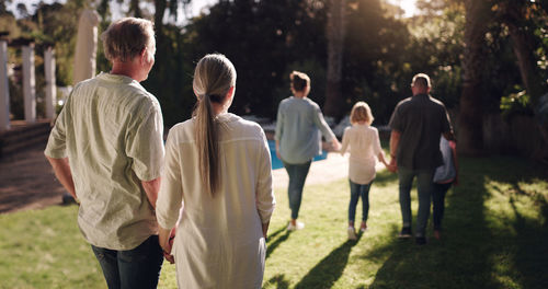 Rear view of people walking on field