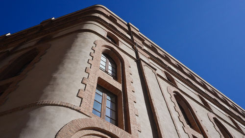 Low angle view of old building against clear blue sky