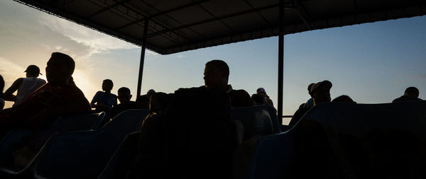 Silhouette people sitting in bus against sky during sunset