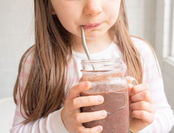 Midsection of girl drinking hot chocolate at home