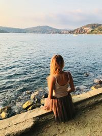 Rear view of woman looking at lake against sky