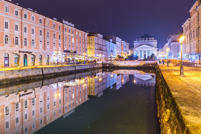 Canal amidst buildings in city at night