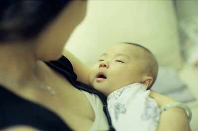 Midsection of mother carrying daughter at home