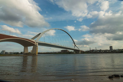 Bridge over river against sky in city