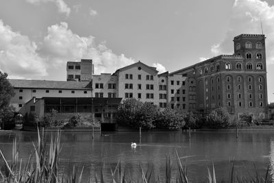 Buildings by lake against sky