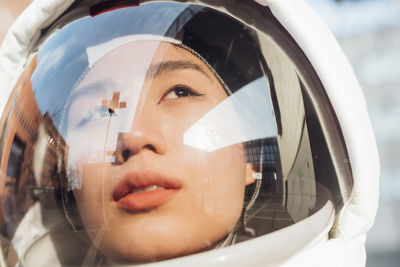 Female astronaut looking away through space helmet during sunny day