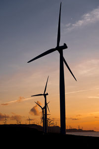 Low angle view of silhouette windmills against sky during sunset