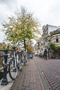 Bicycle on sidewalk by buildings in city against sky
