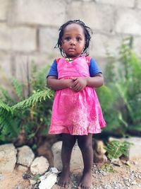 Full length of girl standing with hands clasped by plants