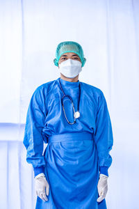 Portrait of doctor wearing mask against white background