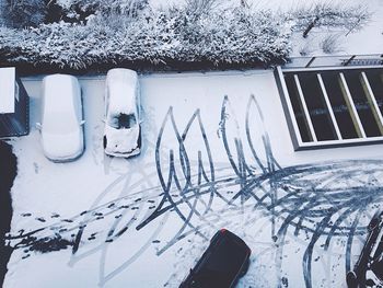 High angle view of tire tracks and cars on snow covered road