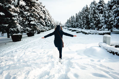 Rear view of woman walking on snow covered land