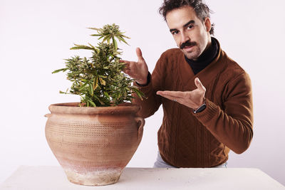 Portrait of woman holding potted plant against white background