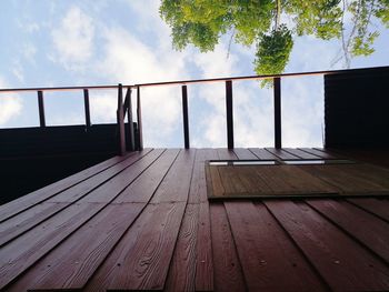 Wooden railing on bridge against sky