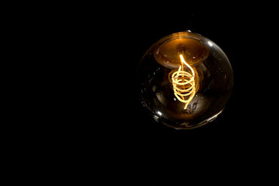 Close-up of illuminated light bulb against black background