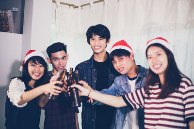 Friends wearing santa hats toasting drinks during christmas party