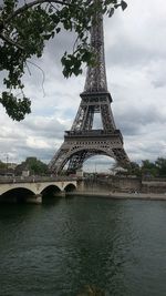 Low angle view of bridge over river against cloudy sky