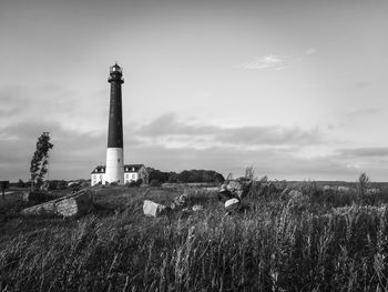 Lighthouse on field against sky