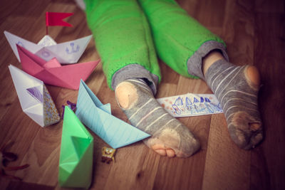 Low section of boy by paper boats on floor