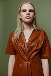 Portrait of young woman standing against wall