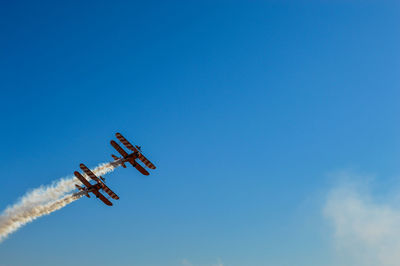 Low angle view of airplane flying against blue sky