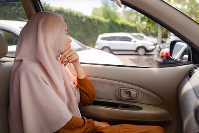 Side view of woman wearing hijab sitting in car