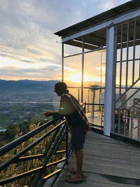 Side view of man standing at balcony while looking at view