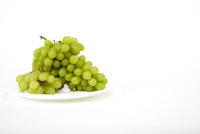 Close-up of grapes in bowl against white background