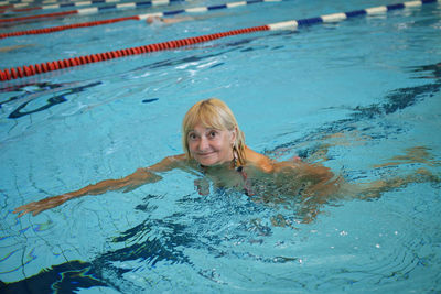 Woman in her 60s swims at public sports pool. slow aging, active lifestyle, health and vitality