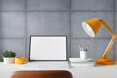 Yellow and coffee cup on table against wall