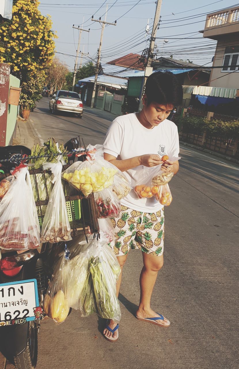 food and drink, food, market, real people, street, retail, market stall, for sale, one person, transportation, casual clothing, city, freshness, day, healthy eating, lifestyles, road, vegetable, small business, outdoors, buying