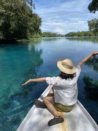 Rear view of woman in hat by lake