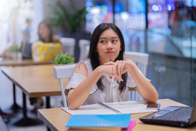 Portrait of a young woman sitting on table