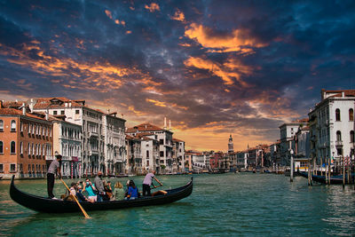 Boats in canal against cloudy sky