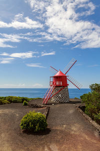 Traditional windmill by sea against sky