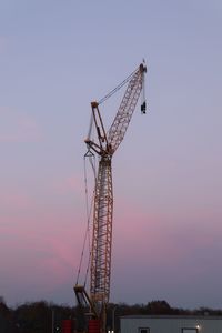 Low angle view of crane against sky at sunset