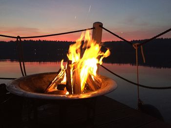 Close-up of fire burning in lake against sky during sunset