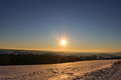 Scenic view of snow covered land during sunset