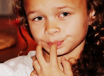 Close-up portrait of girl with finger in mouth